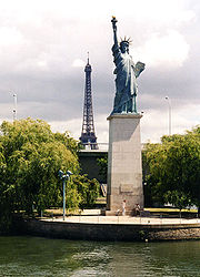 Die Kopie der Freiheitsstatue auf der Île aux Cygnes. Zwei Personen geben einen Größenvergleich