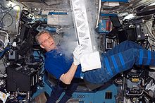 ESA-Astronaut Thomas Reiter arbeitet während der STS-116 Mission mit den Passive Observatories for Experimental Microbial Systems in Micro-G (POEMS) in dem Minus Eighty Degree Laboratory Freezer for ISS (MELFI) des Destiny-Moduls. MELFI ist eine Kühleinrichtung um für Experimente benötigte Materialien auf -80, -26 beziehungsweise +4° zu kühlen.