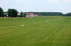Ansicht der Graspiste, im Hintergrund die Flughafengebäude
