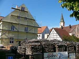 Verbaute Reste der Wasserburg Berolzheim im eingerüsteten Gebäude, im Hintergrund die untere Kirche St. Michael in Markt Berolzheim