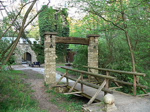 Brücke über den Burggraben mit Eingangsportal, dahinter Burg mit efeubewachsenem Turm