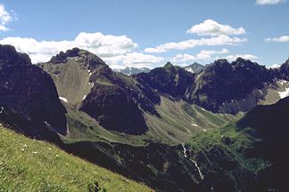 Kemptner Köpfle (grasige Bergspitze etwa in Bildmitte) von Norden, vom Weg von der Kuhgehrenalpe zur Fiderepasshütte. Links davon der Südwestliche Schafalpenkopf, rechts davon die Sechszinkenspitze.