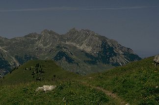 Roßgundkopf (der Gipfel links Bildmitte, links der markanten Scharte) vom Gebiet der Rappenseehütte. Rechts der Scharte der Alpgundkopf. Links im Vordergrund der begraste Mußkopf