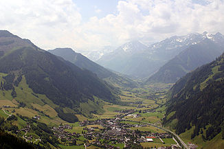 Blick über Rauris taleinwärts, von rechts die Seidlwinklache, von links Vorsterbach, in das Hüttwinkltal, im Hintergrund Ritterkopf, Hocharn und Hoher Sonnblick in Wolken
