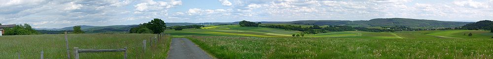 Blick von der Wolfskaute bei Rauschenberg auf Gilserberger Höhen als Teil der Oberhessischen Schwelle, die den Vogelsberg (773 m, ganz rechts im Hintergrund) und den Kellerwald (bis 675,3 m, ganz links) verbindet. Rechts der Burgholz (379,1 m), rechts der Mitte im ferneren Hintergrund der Kirschenwald (bis 532,8 m) im Knüll (bis 635,5 m), links der Mitte die Windkraftanlage von Ernsthausen; ganz links die optisch miteinander verschmolzen scheinenden Jeust (ca. 585 m) und Wüstegarten (675,3 m), am äußersten linken Rand das Hohe Lohr (656,7 m, Fernsehturm)