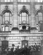 Scheidemann ruft vom Westbalkon (zweites Fenster nördlich des Portikus) des Reichstaggebäudes die Republik aus.