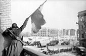 Rotarmist schwenkt die Fahne des Sieges auf dem zentralen Platz, Januar 1943