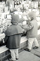 Schwarzweiß-Fotografie von zwei kleinen Kindern, die Süßigkeiten in einem Schaufenster betrachten