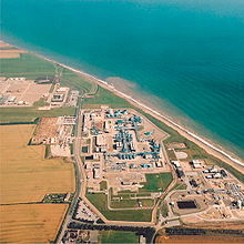 Aerial view of the gridiron arrangement of buildings and pipes beside the curving Yorkshire sea coast.