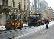 Foto einer städtischen Straßenbaustelle mit Asphaltfertiger und Kombiwalze
