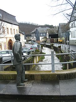 Rhaunelbach mit "Bachspauzer"-Denkmal in Rhaunen