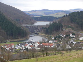 Diemeltalsperre: Staumauer mit See, Ausgleichsweiher und Kraftwerk. Im Vordergrund die Ortschaft Helminghausen. Links der Eisenberg.