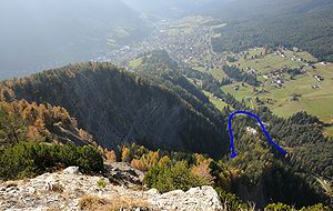 Die Burgruine Stetteneck (in Blau eingekreist) auf dem Col de Pincan, im Hintergrund St. Ulrich in Gröden. Aufnahme vom Balestberg.