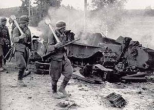 Finnische Soldaten passieren einen zerstörten sowjetischen Panzer T-34