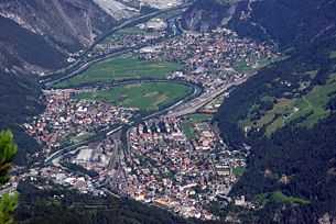 Die Stadt Landeck in Tirol mit der Trasse der Arlbergbahn (im Vordergrund) und dem Bahnhof Landeck-Zams sowie der Inntal Autobahn (A 12)