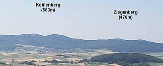 Der Kohlenberg und sein nordöstlicher Nachbar Ziegenberg (470m) vom Christenberg im Burgwald aus; im Vordergrund die Wetschaft-Senke mit dem 324m hohen, bewaldeten Kainsberg bei Münchhausen-Wollmar.