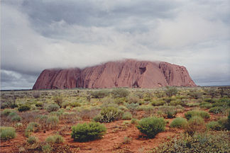Der Uluṟu in Wolken zeigt sich grau