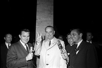 Lyndon B. Johnson zeigt Reportern das Victory-Zeichen