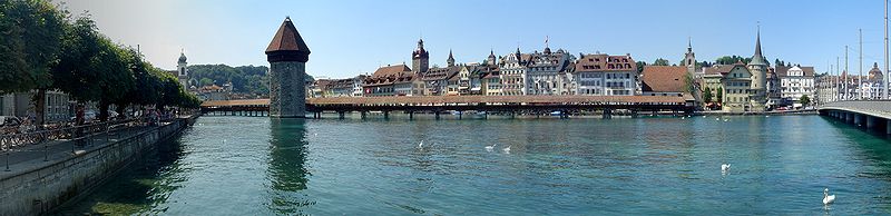 Luzerner Ansicht mit Kapellbrücke, Wasserturm sowie Turm und Bauernhausdach des Rathauses. Zwei Museggtürme lugen über die Dächer der Altstadt, der Wachturm und der Luegisland.