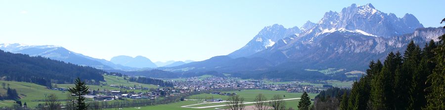 St. Johann von Reitham aus gesehen, rechts im Hintergrund das Kaisergebirge. (Winter)-(Frühling)